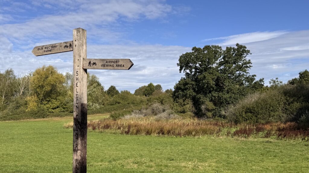 Fingerpost in Sheldon Country Park pointing towards Birmingham Airport viewing area and Old Rectory Farm